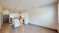 Located at 3310 Women's Club Dr in Raleigh, North Carolina, this two-floor residence offers a thoughtfully designed layout with modern finishes and a bright, airy atmosphere. The open-concept kitchen and living area serves as the heart of the home, featuring crisp white cabinetry, a central island with built-in shelving, and stainless steel appliances including a refrigerator, microwave, and dishwasher. Pendant lighting hangs above the island and a track lighting fixture illuminates the kitchen, creating a warm and functional workspace. Light-toned hardwood-style flooring runs throughout, lending a sense of continuity and cleanliness to the space. Neutral white walls and smooth ceilings contribute to the open, uncluttered feel, while the generous open floor plan provides flexibility for a variety of living arrangements. The two-floor layout offers separation between living and private spaces, making it well-suited for everyday comfort. Overall, the residence combines a clean contemporary aesthetic with practical design, creating a welcoming and functional home in the heart of Raleigh.