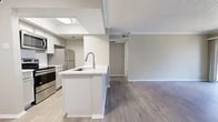 Located at 2300 Fair Oaks Dr in Arlington, TX, this one-bedroom, one-bathroom unit offers a practical and modern layout across a single floor. The open-concept kitchen and living area forms the heart of the space, anchored by a white peninsula with an integrated sink and pull-down faucet. The kitchen is equipped with stainless steel appliances—including a refrigerator, range, and microwave—set against light cabinetry and a classic tile backsplash, all illuminated by flush ceiling lighting.

The living room is bright and welcoming, featuring wood-look plank flooring, crown molding, a textured ceiling, and a white fireplace as a focal point. A sliding glass door opens to a private patio with views of the surrounding greenery, while a side window allows additional natural light to fill the room.

The bedroom is comfortably sized, with a ceiling fan, wood-look flooring, and direct access to both the hallway and a dedicated closet. The bathroom features a vanity with a white countertop, light cabinetry, wood-look flooring, and a full tub-shower combination with white tile surround. The unit is part of a two-story residential building with shared lawn space.