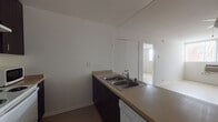 This single-floor unit offers a clean, functional layout designed for comfortable everyday living. The kitchen is equipped with dark espresso cabinetry, a double stainless steel sink, laminate countertops, a white electric range, and a dishwasher. A peninsula counter separates the kitchen from the open living area, which features light hardwood-style flooring, a ceiling fan, and large windows dressed with vertical blinds that invite abundant natural light throughout the space.

The bedrooms are well-proportioned, each featuring light hardwood-style floors, large windows with views of surrounding greenery, and generous closet space with sliding doors and built-in shelving. One bedroom benefits from a wall of floor-to-ceiling windows, further enhancing the bright and airy atmosphere, with direct access to a full bathroom.

Both bathrooms follow a consistent design aesthetic, featuring dark wood vanities with integrated sinks, stone-toned countertops, tiled flooring, and a shower-tub combination enclosed by sliding frosted glass doors. The overall interior palette of crisp white walls, light flooring, and dark cabinetry accents creates a clean, modern contrast throughout the unit.