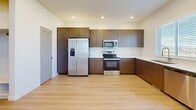 This three-story townhome in Bluffdale, Utah offers a well-organized layout across three distinct floors, providing ample space for comfortable living. The entry level features a open living area with light hardwood-style flooring and recessed lighting. The main living floor showcases an open-concept kitchen and living room combination, where rich dark-wood cabinetry pairs with crisp white countertops and a full suite of stainless steel appliances, including a French door refrigerator, electric range, microwave, and dishwasher. A window above the sink and an adjacent sliding glass door lead to a balcony with scenic views of the surrounding Bluffdale landscape and mountains beyond. The carpeted living area on this floor is bright and open, with recessed lighting and sliding door access to outdoor space. The upper floor hosts all four bedrooms, including a generous primary suite with a walk-in closet featuring built-in shelving and hanging rods. The additional bedrooms are carpeted with large windows that bring in natural light and neighborhood views. Three full bathrooms are finished with tub-shower combinations, light hardwood-style flooring, and clean white surrounds. Hallways connect each level seamlessly, with three staircases ensuring efficient flow throughout this thoughtfully designed multi-level home.