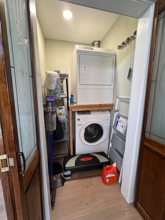 Full-sized stacked washer and dryer behind wooden doors - 1490 Ash St