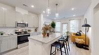 This thoughtfully designed one-bedroom, one-bathroom home offers a modern open-concept layout that maximizes every square foot. Light wood-look flooring flows seamlessly throughout, complementing the bright, neutral color palette that defines the space.

The kitchen is a standout feature, boasting granite countertops, a large center island with bar seating, gray shaker-style cabinetry, a classic subway tile backsplash, and a full suite of stainless steel appliances. Pendant lighting above the island adds a stylish touch. The kitchen opens effortlessly into the living area, which is bathed in natural light from multiple windows and a glass-panel door leading to an outdoor area.

The bedroom is a comfortable retreat featuring large windows that invite ample natural light, a ceiling fan, and continued wood-look flooring. A dedicated walk-in closet provides generous storage with built-in shelving and hanging rods. The bathroom mirrors the home's refined aesthetic with granite countertops, gray cabinetry, and a tub-shower combination adorned with striking marble-look tile surround. A hallway connects the living spaces with functional flow, completing this polished and practical single-floor home.