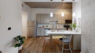 Located in the heart of Charleston's historic district, this 4-bedroom, 3-bathroom residence at 34 Woolfe St offers a compelling blend of industrial and modern design. The space is defined by its striking exposed concrete ceilings, which contrast beautifully with warm hardwood flooring throughout the main living areas.

The open kitchen is well-appointed with contemporary flat-front cabinetry in a light wood finish, a mosaic tile backsplash, stainless steel appliances including a refrigerator, range, microwave, and dishwasher, and a peninsula with pendant lighting — ideal for casual dining or entertaining. The kitchen flows naturally into the living room, which features the same exposed concrete ceiling, large windows that invite natural light, and direct access to a private balcony.

Each of the four bedrooms is carpeted for comfort and offers adequate space for sleeping and working, with several rooms showcasing exposed concrete accents. The three bathrooms are finished consistently with light wood vanities, framed mirrors, tile flooring, and shower-tub combinations. Additional conveniences include an in-unit laundry area, multiple closets for storage, and connecting hallways that provide a functional layout throughout the single-level floor plan.