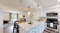 Located at 1000 Old Brook Road in Charlottesville, VA, this two-bedroom, two-bathroom home offers a thoughtfully designed single-floor layout. The open-concept kitchen, dining, and living area serves as the heart of the home, featuring a spacious peninsula with light quartz countertops, crisp white cabinetry, stainless steel appliances, and elegant pendant lighting. The dining area sits just off the kitchen, connected by a graceful arched passageway, while the living room benefits from natural light streaming through large windows with views of surrounding greenery. Wood-look flooring runs throughout the main living areas, adding warmth and continuity. Both bedrooms are carpeted and generously sized, each offering ample natural light through well-dressed windows and convenient access to their own bathroom. The bathrooms are finished in clean, bright whites with wood-look flooring, mirrors, and tub-shower combinations. Three closets throughout the home provide practical storage solutions. The overall ambiance is bright, modern, and welcoming, with a neutral palette that offers a versatile backdrop for a variety of interior styles.
