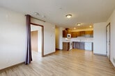 Located at 175 Pump Drive in Burlington, WA, this single-floor, one-bedroom, one-bathroom unit offers a practical and comfortable layout designed to maximize every square foot. Light-toned hardwood-style flooring runs throughout, creating a cohesive and clean aesthetic across all rooms.

The open-concept living, dining, and kitchen area forms the heart of the unit. The kitchen is well-equipped with warm-toned wood upper cabinetry, contrasting gray lower cabinets, and light countertops. White appliances—including an electric range, over-the-range microwave, dishwasher, and refrigerator—provide full functionality. Recessed lighting accents the kitchen, while flush-mount ceiling fixtures illuminate the adjoining living and dining areas. A curtained doorway adds a distinct, casual touch to the room separation.

A hallway connects the main living area to the private bedroom and bathroom. The bedroom is a comfortable, well-proportioned space featuring a large window fitted with horizontal blinds that frame a scenic view of trees and open green landscape—bringing in natural light and a connection to the outdoors. A closet provides dedicated storage.

The bathroom includes a full-size soaking tub and shower combination with clean white surround panels and chrome fixtures, keeping the space simple and functional. The unit's overall design is clean, neutral, and move-in ready.