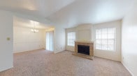 Located in San Antonio's Thousand Oaks neighborhood, this single-floor residence offers a thoughtfully designed layout with a welcoming flow between living spaces. The living room is a standout, featuring vaulted ceilings, plush neutral carpeting, and a classic brick fireplace flanked by windows that allow natural light to fill the room. An arched opening connects the living area to a dedicated dining space, which is accented by an elegant chandelier and sliding glass door access, ideal for entertaining. The kitchen is efficiently laid out with warm wood cabinetry, laminate countertops, hardwood-style flooring, and white appliances including a range, microwave, and dishwasher. A pass-through counter connects the kitchen to the adjacent living area, enhancing the open feel of the home. The bedrooms are generously sized, each with soft carpeting and ample natural light from well-placed windows. One bedroom features a sliding glass door with vertical blinds and a ceiling fan, adding comfort and versatility. The bathrooms include a vanity with wood cabinetry and granite-style countertops, a tub-shower combination, and hardwood-style flooring. Throughout the residence, a neutral color palette, consistent finishes, and practical design create a cohesive and comfortable living environment.