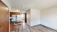 Located at 2109 College St in Cedar Falls, Iowa, this one-bedroom, one-bathroom unit offers an efficient and practical layout across a single floor. The open living and kitchen area features durable hardwood-style flooring, neutral walls, and a textured ceiling throughout, creating a clean and cohesive look. The kitchen is well-equipped with warm wood cabinetry, dark laminate countertops, a built-in breakfast bar, a double sink, an electric range, and a full-size refrigerator, providing ample prep and storage space for everyday cooking. A dishwasher is also included. The living area flows naturally from the kitchen, offering a flexible space for both relaxing and entertaining. The bedroom is a comfortable size, featuring plush carpet, two wood-paneled closets for generous storage, and a window with blinds that allows natural light and outdoor views. The bathroom is straightforward and functional, complete with a toilet, a combination tub and shower unit, and an open shelving area above. A wall-mounted air conditioning unit services the space, and central ventilation is present throughout. This unit is an ideal option for those seeking a practical, no-frills living space in Cedar Falls.