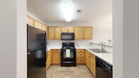 Located at 3250 Carter Rd in Sumter, South Carolina, this single-story, three-bedroom, two-bathroom home offers a well-organized and functional layout. The combined kitchen and living room serves as the heart of the home, with the living area featuring plush carpeting, a ceiling fan with light fixture, and a glass door that fills the space with natural light and provides outdoor access. The kitchen is equipped with warm honey-toned wood cabinetry, light countertops, and a full suite of black appliances including a refrigerator, electric range, over-the-range microwave, and dishwasher, all set over wood-look flooring. The three bedrooms are carpeted and finished in neutral tones, offering a clean and versatile canvas. The generously sized primary bedroom provides ample space. Both bathrooms feature tub-shower combinations with curtain rods, wood-look flooring, and clean white finishes. One bathroom includes a built-in shelving unit for additional storage. A dedicated laundry closet houses a full-size washer and dryer. A separate closet with wire shelving adds further storage convenience throughout this practical and comfortable home.