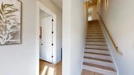 Located in Fort Worth, TX, this contemporary 3-story home offers a well-designed layout spread across three distinct levels. The entry level provides a welcoming foundation, while the main living floor showcases a bright, open-concept kitchen and living area. The kitchen is a standout, featuring white shaker cabinetry, stone countertops, a large center island with seating, a gas range with a wall-mounted hood, stainless steel appliances, and elegant tile backsplash. The living area flows naturally from the kitchen, bathed in natural light from large French doors that open to an outdoor balcony. A ceiling fan and recessed lighting complete the airy atmosphere. The upper floor hosts two well-proportioned bedrooms, each with direct balcony access and generous natural light. The spacious primary bedroom offers hardwood-style flooring and private outdoor views. A dedicated office with large windows provides an ideal workspace. The four bathrooms are finished with large-format tile flooring, white cabinetry, dark stone countertops, and matte black hardware. The home also includes a laundry room, multiple closets, and two staircases connecting all levels, finished with light wood treads and clean white walls throughout.