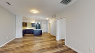 Located at 126 W Mishawaka Ave in Mishawaka, Indiana, this single-floor unit offers a thoughtfully designed open-concept layout that seamlessly connects the living, dining, and kitchen areas. Rich hardwood-style flooring flows throughout the entire space, creating a cohesive and contemporary aesthetic.

The kitchen is a functional centerpiece, outfitted with dark espresso cabinetry, white countertops, a full suite of black appliances including a refrigerator, range, built-in microwave, and dishwasher, as well as a kitchen island that provides additional prep and dining space. Track lighting and pendant fixtures illuminate the space effectively. A vibrant yellow backsplash accent adds a touch of warmth to the kitchen's bold color scheme.

The living area is generously proportioned, featuring a ceiling fan and large sliding glass doors that invite natural light and provide access to an outdoor area. Adjacent rooms offer flexible use, with neutral-toned walls and windows dressed with horizontal blinds. A walk-in closet with wire shelving systems provides ample storage. The bathroom is well-appointed with dark wood cabinetry, a white countertop vanity, large mirrors, and a tub-shower combination. The overall ambiance is clean, modern, and move-in ready.