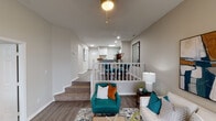 Located at 7858 Island Club Dr in Indianapolis, Indiana, this well-appointed single-floor residence showcases a thoughtfully designed split-level interior with a welcoming, open-concept flow. The living area features hardwood-style flooring, a white railing overlook, and a warm, layered aesthetic enhanced by contemporary artwork and teal accent furnishings.

The kitchen is a standout, outfitted with stainless steel appliances, granite countertops, white shaker cabinetry, and a peninsula that opens directly to the dining area — ideal for both everyday living and entertaining. A skylight overhead brightens the space naturally.

The bedrooms offer comfort and personality, with plush carpeting, vaulted ceilings, and large windows that invite natural light. A bold teal accent wall in one bedroom adds a striking design touch, while the primary bedroom features a tufted upholstered headboard and generous window coverage with layered curtains and blinds.

The bathrooms are finished with tiled tub/shower surrounds, wood-look tile accents, and granite vanity surfaces, creating a clean and cohesive look. The overall color palette of warm grays, whites, and teal accents carries consistently throughout the home, lending it a modern yet inviting ambiance.