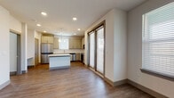 Located in Georgetown, TX, this well-designed single-story residence offers a clean, modern aesthetic throughout. The open-concept layout connects the living area and kitchen seamlessly, with warm wood-look luxury vinyl plank flooring extending across the main living spaces. Large sliding glass doors and multiple windows flood the interior with natural light, creating an airy, inviting atmosphere.

The kitchen is a standout feature, outfitted with soft gray shaker-style cabinetry, crisp white quartz countertops, a central island with pendant lighting, and a full suite of stainless steel appliances including a refrigerator, range, microwave, and dishwasher. The space is both functional and visually cohesive.

The bedrooms are comfortably sized, each featuring wood-look flooring, ceiling fans, and windows that bring in natural light. The primary bathroom impresses with its marble-look tile flooring and wall surround, a dual-sink vanity topped with white quartz, soft blue-gray cabinetry, and brushed nickel hardware. A secondary bathroom mirrors the refined finishes with a single-sink vanity and overhead cabinetry.

Throughout the residence, neutral tones, recessed lighting, and consistent finishes create a cohesive and contemporary living environment well-suited to everyday comfort.