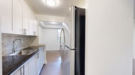 Located at 1835 Bayview Avenue in Toronto's sought-after Leaside neighbourhood, this one-bedroom, one-bathroom unit offers a practical and well-proportioned layout across a single floor. Rich, dark parquet hardwood flooring flows consistently throughout the living spaces, adding warmth and classic character to the interior.

The spacious living room is a standout feature, bathed in natural light from a wide, low-profile window that overlooks the street and surrounding greenery. A radiator beneath the window provides efficient heating. The open, clean-lined design of the living area creates a versatile space suitable for a variety of furniture arrangements.

The bedroom is generously sized, featuring its own window with an outdoor view, a radiator, and a built-in double-door closet offering ample storage. The same polished parquet flooring continues here, maintaining a cohesive aesthetic throughout.

The bathroom is finished with classic white subway tile surrounding a full soaker bathtub and shower combination. A dark stone countertop vanity with an undermount sink adds a subtle contrast to the bright, clean surroundings. A small frosted window allows for natural light and ventilation.

A connecting hallway ties the rooms together efficiently, completing a layout that is both functional and comfortable for single occupancy or couples.