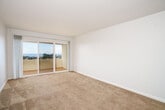 Located at 335 Talbot Ave in Pacifica, CA, this one-bedroom, one-bathroom residence offers a thoughtfully laid-out single-floor plan with a comfortable and functional living environment. The living room features plush carpeting and a wall-mounted heater, with an open sightline into a dedicated dining area illuminated by a pendant light fixture. Sliding glass doors lead from the living space to a private balcony, offering expansive views of the surrounding Pacifica landscape — a standout feature of this home. The kitchen is neatly appointed with white cabinetry, speckled countertops, a stainless steel sink, and includes a dishwasher and refrigerator, with light wood-style flooring tying the space together. A hallway connects the main living areas to the bedroom, which is generously sized with soft carpet flooring, a large window inviting natural light, and a mirrored sliding-door closet. An additional closet provides further storage. The bathroom is clean and efficient, featuring a tub/shower combination, a granite-topped vanity, and wood-style tile flooring. Throughout, the neutral color palette and clean lines create a bright, cohesive ambiance well-suited to comfortable everyday living.