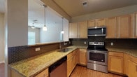 This single-floor residence offers a practical and comfortable layout designed to maximize everyday living. The open-concept living area features warm hardwood-style flooring, neutral toned walls, and a ceiling fan, with large windows that invite generous natural light throughout. A pass-through from the kitchen keeps the space feeling connected and airy.

The kitchen is well-equipped and thoughtfully designed, featuring light maple cabinetry with ample storage, granite countertops, a mosaic tile backsplash, and a full suite of stainless steel appliances including a refrigerator, electric range, over-the-range microwave, and dishwasher. Pendant lighting above the breakfast bar adds a polished touch, while the hardwood-style flooring carries throughout for a cohesive look.

The bedroom is a quiet retreat, finished with plush wall-to-wall carpet, a ceiling fan with light fixture, and a window with blinds that allows for natural light while maintaining privacy.

The bathroom is clean and functional, featuring tile-surround tub and shower combination, hardwood-style flooring, and crisp white fixtures. The overall design of the residence balances practicality with modern comfort, making it a well-rounded living space suitable for a variety of lifestyles.