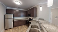 This single-floor residence offers a thoughtfully designed layout that balances functionality and modern style throughout. The kitchen serves as a standout feature, showcasing rich dark-espresso cabinetry, granite countertops with subtle speckled detailing, a classic white subway tile backsplash, and a full suite of stainless steel appliances including a refrigerator, electric range, over-the-range microwave, and dishwasher. Light wood-style flooring runs through the kitchen and living areas, complementing the neutral warm-gray wall tones that carry throughout the home. A pendant light and flush-mount ceiling fixture provide balanced illumination in the kitchen.

The living area is generously proportioned, featuring crown molding, a ceiling fan with integrated lighting, recessed lighting, and a window that allows natural light to fill the room. The bedrooms are finished with plush carpeting and include windows fitted with horizontal blinds, offering both comfort and privacy. A ceiling fan in one bedroom adds an additional layer of comfort. Walk-in closet space with wire shelving systems provides practical storage solutions.

The bathroom is well-equipped with a dual-sink vanity featuring granite countertops, dark cabinetry, framed mirrors, and brushed nickel hardware. A tub-shower combination with built-in shelving completes the bath. Wood-look flooring ties the bathroom's design cohesively to the rest of the home.