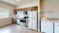 Located at 4570 49th Ave S in Fargo, North Dakota, this single-floor unit offers a well-appointed and efficiently designed living space. The kitchen is a functional highlight, featuring stainless steel appliances including a refrigerator, electric range, and built-in microwave, all complemented by rich dark-wood cabinetry with brushed nickel hardware and a double basin sink. Conveniently situated adjacent to the kitchen is an in-unit laundry area, adding everyday practicality to the layout.

The open living area benefits from light-toned luxury vinyl plank flooring that extends throughout much of the unit, contributing to a clean and cohesive aesthetic. Natural light enters through a large window fitted with blinds, brightening the combined living and kitchen space. Architectural column details add subtle visual interest to the layout, while transitions between flooring materials help define distinct functional zones.

The bathroom is finished with a warm wood-tone vanity, stone-patterned countertop, a large mirror, and wood-look flooring, creating a tidy and tasteful space. Overall, the unit presents a neutral color palette, modern fixtures, and practical amenities suited for comfortable everyday living.