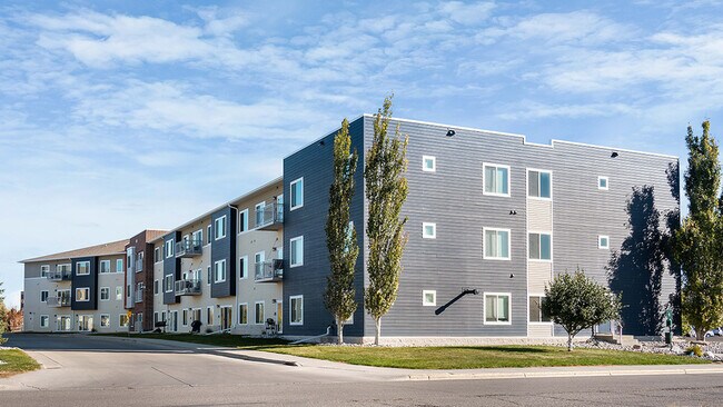 Edificio de apartamentos moderno con una fachada elegante, que cuenta con varios balcones y está rodeado de vegetación, bajo un cielo azul despejado. - Mallview Apartments