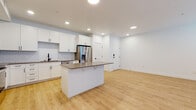 This single-floor residence offers a clean, contemporary design with a cohesive color palette of white and neutral tones throughout. The open-concept kitchen is a standout feature, equipped with white shaker-style cabinetry, a classic subway tile backsplash, a full suite of stainless steel appliances including a French door refrigerator, microwave, and range, as well as a central island with a taupe quartz countertop and bar seating. Light wood-look flooring extends seamlessly from the kitchen into the adjacent living area, which is bright and airy thanks to multiple windows fitted with horizontal blinds. The bedrooms are finished with plush neutral carpet and ceiling fans, and receive generous natural light through large windows. A walk-in closet with built-in hanging rods provides ample storage. The bathroom maintains the same modern aesthetic, featuring white cabinetry, a taupe countertop with an undermount sink, matte black hardware and fixtures, a large vanity mirror, and a shower-tub combo. Recessed lighting throughout the main living areas ensures consistent, well-distributed illumination. The overall ambiance is fresh, modern, and move-in ready.