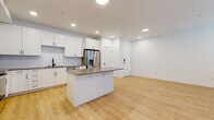 This single-floor residence offers a clean, contemporary design with a cohesive color palette of white and neutral tones throughout. The open-concept kitchen is a standout feature, equipped with white shaker-style cabinetry, a classic subway tile backsplash, a full suite of stainless steel appliances including a French door refrigerator, microwave, and range, as well as a central island with a taupe quartz countertop and bar seating. Light wood-look flooring extends seamlessly from the kitchen into the adjacent living area, which is bright and airy thanks to multiple windows fitted with horizontal blinds. The bedrooms are finished with plush neutral carpet and ceiling fans, and receive generous natural light through large windows. A walk-in closet with built-in hanging rods provides ample storage. The bathroom maintains the same modern aesthetic, featuring white cabinetry, a taupe countertop with an undermount sink, matte black hardware and fixtures, a large vanity mirror, and a shower-tub combo. Recessed lighting throughout the main living areas ensures consistent, well-distributed illumination. The overall ambiance is fresh, modern, and move-in ready.