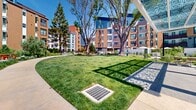 Located at 777 W Middlefield Road in Mountain View, California, this contemporary residential community showcases a thoughtfully designed outdoor environment that seamlessly blends modern architecture with vibrant natural landscaping. The multi-story buildings feature a dynamic palette of blue, green, terracotta, and white paneling, complemented by private balconies and large windows that invite abundant natural light.

The outdoor grounds are the defining feature of this community, offering a series of interconnected courtyards and pedestrian pathways that wind through rich, layered plantings of native grasses, flowering shrubs, and mature trees. Raised wood-framed planter beds add warmth and structure to the hardscaped areas, while open lawn sections provide generous green space beneath the canopy of established trees.

Decorative paved plazas, curved seating elements, and strategically placed lighting fixtures create welcoming gathering areas throughout the grounds. Clearly marked directional signage guides residents to key amenities including leasing and rideshare areas. Picnic tables and shaded spots offer additional spaces for relaxation and socializing. The overall ambiance is one of a well-curated, park-like setting that fosters a strong sense of community within the heart of Mountain View.