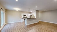 Located at 313 Creek in Wayne, PA, this well-appointed single-floor home offers three bedrooms, two bathrooms, and a thoughtfully designed layout. The open-concept kitchen and living area serves as the heart of the home, showcasing a peninsula with dark granite countertops, white shaker cabinetry, stainless steel appliances including a range, microwave, and refrigerator, and stylish pendant lighting overhead. A skylight adds an extra dose of natural light, complementing the warm light wood-look flooring that flows throughout the main living areas. Large windows and a door with outdoor balcony access bring in generous views of the surrounding greenery. The spacious primary bedroom is a standout, offering ample room to furnish comfortably. All bedrooms feature plush carpeting, ceiling fans, and windows overlooking the outdoors. The two bathrooms are finished in a clean, modern style — one featuring a soaking tub framed by elegant marble-look tile surround with a built-in shelf, and both featuring white vanities with bright vanity lighting. Additional storage is provided by two dedicated closets, and two hallways connect the spaces efficiently. Neutral warm-gray tones and clean white trim throughout create a cohesive and inviting atmosphere.