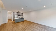 This two-story residence in Wilmington, Delaware offers a thoughtfully designed layout spread across two well-proportioned floors. The main level features an open-concept kitchen and living area with light hardwood-style flooring, recessed lighting, and large windows that invite natural light and street-level views. The kitchen is a standout, equipped with sleek gray cabinetry extending to the ceiling, stainless steel appliances, a microwave, range, and refrigerator, all anchored by a generous island with a crisp white countertop, undermount sink, and pendant lighting overhead.

The living area flows seamlessly from the kitchen, offering a clean, minimalist aesthetic with bright white walls and a staircase leading to the upper floor. Upstairs, the spacious primary bedroom provides an expansive retreat, while the second bedroom is well-sized with hardwood-style flooring and ample natural light through a large window overlooking the neighborhood.

All three bathrooms are finished with striking large-format marble-look tile, featuring both a walk-in glass-enclosed shower and a soaking tub with a curved shower rod in separate bathrooms. A well-organized closet with built-in shelving and hanging rods adds practical storage. The overall design is modern, clean, and move-in ready.