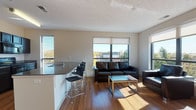 Located at 401 S Main St in downtown Akron, Ohio, this modern single-floor unit offers a well-designed open-concept layout with contemporary finishes throughout. The living area is bright and inviting, featuring rich hardwood-style flooring, large windows with roller shades that frame views of the surrounding cityscape, and ample natural light. The living room flows seamlessly into the kitchen, which is outfitted with dark cabinetry, granite countertops, black appliances including a refrigerator, range, and dishwasher, and a peninsula with bar seating that doubles as a casual dining area.

The unit includes multiple bedrooms, each with hardwood-style flooring, natural light from windows, and practical built-in closet shelving for organized storage. One bedroom also features a dedicated desk area, making it suitable for a home office setup.

The bathrooms are finished with slate-style tile flooring and clean white fixtures. A full bathroom includes a tub-shower combination, while a second bathroom also offers a tub-shower setup alongside a granite-topped vanity with dark cabinetry. The neutral color palette and consistent finishes throughout contribute to a clean, modern ambiance well-suited for urban living.