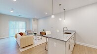 Located at 9606 Lamont Avenue in Cleveland's 44106 neighborhood, this single-floor unit offers a thoughtfully designed layout that maximizes both functionality and comfort. The open-concept living and kitchen area serves as the heart of the space, where light hardwood-style flooring, recessed lighting, and soft neutral walls create a bright, modern ambiance. The kitchen is outfitted with stainless steel appliances — including a French door refrigerator and range — white shaker cabinetry, and a granite-topped island with an undermount sink and pendant lighting, providing convenient seating for casual dining. The living area flows naturally from the kitchen, offering generous room for lounge seating and accent furniture, with sliding glass door access that invites natural light throughout. The bedroom is a serene retreat, featuring plush carpeting, wide horizontal-blind windows for privacy and light control, and a spacious walk-in closet equipped with wire shelving for ample storage. The bathroom is finished with a floating white vanity, brushed nickel fixtures, a rounded-corner mirror, and wood-look flooring, delivering a clean and contemporary feel. Raised panel interior doors and consistent trim work throughout lend a polished, cohesive character to the entire unit.