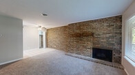 Located at 3002 E 51st St in Tulsa, Oklahoma, this one-bedroom, one-bathroom unit offers a thoughtfully organized single-floor layout. The living room serves as the centerpiece of the space, highlighted by a striking full-width exposed brick wall with a wood-burning fireplace and a rustic mantle. Plush carpeting and a large front-facing window allow natural light to fill the room, creating a warm and inviting atmosphere. The living area transitions seamlessly into the galley-style kitchen, which features white cabinetry, granite countertops, tile flooring, recessed lighting, and stainless steel appliances including a gas range, refrigerator, and dishwasher. The bedroom is a comfortable retreat with soft carpet, a ceiling fan, a window with outdoor views, and access to two closets — one of which is a walk-in — providing ample storage. The full bathroom is clean and functional, offering a tiled tub-shower combination, modern brushed nickel fixtures, and wood-look flooring. Neutral tones throughout the unit lend a cohesive and move-in ready aesthetic, making this Tulsa residence a practical and comfortable home.