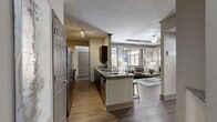 This single-floor, 3-bedroom, 2-bathroom residence offers a thoughtfully designed open-concept layout that seamlessly connects the kitchen, living, and dining areas. The kitchen is a standout feature, equipped with dark espresso cabinetry, stainless steel appliances, a decorative tile backsplash, and a granite-topped island with bar seating — ideal for both cooking and casual dining. A galley-style counter runs the length of the kitchen, maximizing workspace and storage.

The living room features a distinctive tray ceiling with a ceiling fan, rich hardwood-style flooring, and neutral tones that create a warm, welcoming ambiance. Large windows allow generous natural light to flow throughout. The dining area is highlighted by soft blue walls, an elegant pendant light, and a large window that brings in additional brightness.

Both bathrooms are finished with granite vanity tops, dark wood cabinetry, and hardwood-style flooring, offering a consistent and polished aesthetic. The primary bedroom is a comfortable retreat with a ceiling fan and a large window that fills the room with natural light.

A connecting hallway with plush carpeting links the bedrooms to the main living spaces. Two closets provide ample storage. The overall design blends modern finishes with a warm, neutral palette throughout.