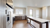Located at 344f Emerson St in Englewood, Colorado, this well-appointed two-bedroom, two-bathroom residence offers a thoughtfully designed single-floor layout. The modern kitchen is a standout feature, showcasing dark wood-toned cabinetry with black hardware, white quartz countertops, stainless steel appliances including a built-in microwave, range, and dishwasher, complemented by light hardwood-style flooring and a tile backsplash. A large kitchen island provides additional prep and dining space. Natural light flows through multiple windows fitted with horizontal blinds. The living room continues the hardwood-style flooring and offers a bright, open feel with access to a private balcony. Both bedrooms are carpeted and neutral in tone; the primary bedroom includes two closets for generous storage. The bathrooms feature matching dark wood vanities with white countertops and wood-style flooring. A dedicated laundry area houses a stacked Whirlpool washer and dryer for added convenience. Throughout the residence, clean white walls, recessed lighting, and consistent finishes create a cohesive, modern aesthetic suitable for comfortable everyday living.