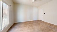 Located at 147 N New Hampshire Ave in the heart of Los Angeles, CA, this efficiently designed single-floor unit offers a thoughtfully arranged layout comprising a living room, kitchen, and two bathrooms. The interior is finished with light wood-style vinyl flooring that runs consistently throughout, contributing to a bright and cohesive feel across the space. Crisp white walls and clean baseboards reinforce the modern, minimalist aesthetic.

The living area is airy and open, benefiting from natural light admitted through a sliding window with a classic iron security grille. A ceiling fan provides year-round comfort and adds a functional design element to the room. The entry door features gold-toned hardware, lending a subtle contemporary accent.

The kitchen is well-appointed with gray shaker-style cabinetry on both the upper and lower levels, complemented by brushed nickel hardware and a white countertop surface. A stainless steel undermount sink with a modern pull-down faucet serves as a practical centerpiece, while ample cabinet storage maximizes the utility of the space.

The two bathrooms include a bathtub with white tile surround, offering clean and functional facilities. A built-in floor-level access panel is also present, adding a practical infrastructure detail. Overall, the unit presents a refreshed, move-in-ready environment ideal for urban living in Los Angeles.