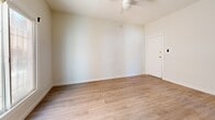 Located at 147 N New Hampshire Ave in the heart of Los Angeles, CA, this efficiently designed single-floor unit offers a thoughtfully arranged layout comprising a living room, kitchen, and two bathrooms. The interior is finished with light wood-style vinyl flooring that runs consistently throughout, contributing to a bright and cohesive feel across the space. Crisp white walls and clean baseboards reinforce the modern, minimalist aesthetic.

The living area is airy and open, benefiting from natural light admitted through a sliding window with a classic iron security grille. A ceiling fan provides year-round comfort and adds a functional design element to the room. The entry door features gold-toned hardware, lending a subtle contemporary accent.

The kitchen is well-appointed with gray shaker-style cabinetry on both the upper and lower levels, complemented by brushed nickel hardware and a white countertop surface. A stainless steel undermount sink with a modern pull-down faucet serves as a practical centerpiece, while ample cabinet storage maximizes the utility of the space.

The two bathrooms include a bathtub with white tile surround, offering clean and functional facilities. A built-in floor-level access panel is also present, adding a practical infrastructure detail. Overall, the unit presents a refreshed, move-in-ready environment ideal for urban living in Los Angeles.