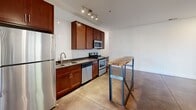 Located at 300 S Skyloft Dr in Asheville, NC, this 2-bedroom, 1-bathroom residence offers a thoughtfully designed single-floor layout with a cohesive modern industrial aesthetic. Polished concrete floors extend throughout the entire home, providing a sleek, low-maintenance surface that reflects natural light and ties each room together visually.

The open living room is bright and airy, featuring recessed lighting, a ceiling fan, and multiple windows alongside a glass-panel exterior door that invites natural light and outdoor views. The galley-style kitchen is well-appointed with rich cherry wood cabinetry, dark granite countertops, a white subway tile backsplash, and a full suite of stainless steel appliances including a range, microwave, dishwasher, and refrigerator. Track lighting overhead illuminates the workspace efficiently.

The primary bedroom showcases a striking reclaimed wood accent wall that adds warmth and texture, complemented by a ceiling fan and a dedicated closet with built-in shelving. The second bedroom is clean and bright with white walls and polished floors. The bathroom features a tub/shower combination with white tile surround, a granite-topped vanity with cherry cabinetry, and consistent finishes matching the rest of the home. A stacked washer/dryer unit is discreetly housed behind louvered sliding closet doors, adding in-unit laundry convenience.