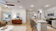 This thoughtfully designed 2-bedroom, 2-bathroom residence in Baton Rouge, Louisiana offers a bright and modern living experience across a single floor. The open-concept layout seamlessly connects the kitchen and living area, creating an inviting, functional space. The kitchen is outfitted with gray shaker-style cabinetry, stainless steel appliances, granite countertops, and a generous island with bar seating — ideal for both casual dining and entertaining. Light wood-tone flooring flows throughout, enhancing the clean, contemporary aesthetic. The living room features a ceiling fan, neutral walls, and French doors that open to an outdoor area, filling the space with natural light. The primary bedroom is comfortably sized, featuring a ceiling fan and access to a walk-in closet with built-in shelving and ample storage. The second bedroom is bright and airy, with large windows dressed in sheer curtains. Both bathrooms echo the home's refined style, with granite vanity countertops and gray cabinetry. A dedicated closet provides additional storage convenience. The overall ambiance is clean, modern, and welcoming — well-suited for comfortable everyday living in the heart of Baton Rouge.
