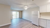 Located at 1371 Parkside Dr in San Bernardino, CA, this one-bedroom, one-bathroom unit offers a thoughtfully organized layout across a single floor. Light wood-look flooring runs throughout, complementing the neutral warm-beige walls and white trim that create a clean, cohesive aesthetic.

The open-concept living room and kitchen area is bright and welcoming, anchored by a ceiling fan with light fixture and a textured ceiling. A sliding glass door opens to a private balcony, filling the space with natural light and offering pleasant outdoor views of surrounding greenery. The kitchen is efficiently laid out in an L-shape, featuring crisp white shaker-style cabinetry, light countertops, a stainless sink, and a full suite of white appliances including a refrigerator, electric range, and over-the-range microwave.

The bedroom is a comfortable, well-proportioned room with a window that brings in natural light and an installed wall AC unit for climate control. It includes access to a dedicated walk-in closet with dual hanging rods and upper cabinetry for ample storage.

The bathroom is equipped with a vanity with white cabinetry, a mirrored medicine cabinet, and accessibility-friendly grab bars. Wood-look flooring continues seamlessly throughout the unit, reinforcing the space's unified, modern design.