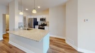 This single-floor residence offers a thoughtfully designed layout that blends modern finishes with comfortable, functional living. The open-concept kitchen and living area serves as the heart of the home, featuring warm hardwood-style flooring, recessed lighting, and a ceiling fan. The kitchen is outfitted with white shaker cabinetry, stainless steel appliances including a gas range and French door refrigerator, and a granite-topped peninsula with pendant lighting and a double sink — ideal for both everyday meals and entertaining. The living area extends toward a sliding glass door that opens to a balcony, offering a bright and airy atmosphere with water views beyond.

The bedrooms are carpeted for comfort, with neutral walls and ample natural light through large windows. One bedroom offers a particularly striking view of the adjacent waterway, while another faces a street-side window. The primary bathroom features hardwood-style flooring, a granite vanity, and a glass-enclosed walk-in shower, with a walk-in closet conveniently nearby. The secondary bathroom mirrors the clean aesthetic with a soaking tub and shower combo, granite countertops, and matching hardwood-style floors. A dedicated utility room houses a stacked washer and dryer alongside a water heater, completing this well-equipped residence.