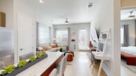 Located in Hutto, TX, this well-designed single-story residence offers a thoughtful open-concept layout that maximizes its efficient footprint. Light wood-tone flooring flows seamlessly throughout the entire unit, creating a cohesive and airy aesthetic.

The combined kitchen and living area serves as the heart of the home. The modern kitchen features flat-front cabinetry in a warm wood finish, white quartz countertops, a subway tile backsplash, and a full suite of stainless steel appliances including a gas range, microwave, dishwasher, and refrigerator. A dining table with a marble-look top and bar seating bridges the kitchen and living area. The living room receives generous natural light through multiple large windows with plantation-style blinds, and a private exterior door provides additional access and light.

The bedroom is a comfortable retreat, featuring a ceiling fan, a window with exterior views, and access to a dedicated closet. The hallways connecting the rooms add to the unit's smart flow.

The bathroom is finished with clean, contemporary materials, including a light wood vanity with quartz countertops, a large mirror, and a glass-enclosed walk-in shower with white tile surround. The consistent use of light wood flooring ties the bathroom seamlessly to the rest of the unit.