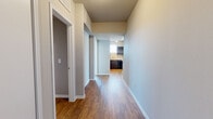 This single-floor residence offers a thoughtfully designed layout with a clean, modern aesthetic throughout. Rich hardwood-style flooring flows through the main living areas, hallways, and kitchen, providing a warm and cohesive look. The open living area benefits from abundant natural light through large sliding glass doors that lead to a balcony, offering expansive outdoor views and creating a bright, airy atmosphere. A tray ceiling detail adds architectural interest to the living space.

The kitchen is well-equipped, featuring dark espresso cabinetry, light granite-style countertops, and black appliances including an electric range with overhead microwave. A functional hallway connects the main living areas to the private quarters, with convenient storage solutions along the way.

The bedrooms feature plush wall-to-wall carpeting and ceiling fans, with windows providing natural light. Each bedroom includes access to a walk-in closet with built-in shelving for ample storage. The bathrooms are outfitted with dark wood vanity cabinetry, light countertops, and hardwood-style flooring. One bathroom includes a glass-enclosed walk-in shower, while another features a full soaking tub with tile surround and direct access to a walk-in closet, enhancing the sense of a private retreat.