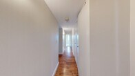Located at 150 Huntington Ave in Boston's vibrant Back Bay/Fenway neighborhood, this one-bedroom, one-bathroom unit offers a well-organized, efficient layout across a single floor. The combined kitchen and living area forms the heart of the unit, where a pass-through breakfast bar connects the two spaces seamlessly. The kitchen is well-appointed with warm maple cabinetry, granite countertops, a mosaic tile backsplash, and a full suite of stainless steel appliances including a refrigerator, range, microwave, and dishwasher, all set atop rich hardwood flooring. The carpeted living area flows naturally from the kitchen, providing a comfortable and functional space. The bedroom offers a generous footprint with plush carpet, a built-in closet with shelving, and large windows that frame impressive views of the Boston skyline and surrounding cityscape, filling the room with natural light. The bathroom features tile surround walls, a granite-topped vanity, and brushed nickel fixtures. A long hallway connects all areas of the unit, lined with clean white walls and continuing the hardwood flooring. The neutral color palette and clean finishes throughout create a bright, move-in-ready atmosphere.