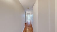 Located at 150 Huntington Ave in Boston's vibrant Back Bay/Fenway neighborhood, this one-bedroom, one-bathroom unit offers a well-organized, efficient layout across a single floor. The combined kitchen and living area forms the heart of the unit, where a pass-through breakfast bar connects the two spaces seamlessly. The kitchen is well-appointed with warm maple cabinetry, granite countertops, a mosaic tile backsplash, and a full suite of stainless steel appliances including a refrigerator, range, microwave, and dishwasher, all set atop rich hardwood flooring. The carpeted living area flows naturally from the kitchen, providing a comfortable and functional space. The bedroom offers a generous footprint with plush carpet, a built-in closet with shelving, and large windows that frame impressive views of the Boston skyline and surrounding cityscape, filling the room with natural light. The bathroom features tile surround walls, a granite-topped vanity, and brushed nickel fixtures. A long hallway connects all areas of the unit, lined with clean white walls and continuing the hardwood flooring. The neutral color palette and clean finishes throughout create a bright, move-in-ready atmosphere.