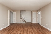 This two-story home in Auburn, Alabama is thoughtfully laid out across two levels, offering a functional and comfortable living environment. The main floor features rich, dark hardwood-style flooring that runs throughout the open living areas, complementing the neutral beige walls and textured ceilings. A carpeted staircase with a white balustrade connects the two floors, while louvered closet doors and a front entry with a transom window add classic architectural details.

The kitchen is outfitted with white cabinetry, dark countertops, a double-basin sink beneath a natural light-filled window, and black appliances including a range and dishwasher. Crown molding adds a refined touch to this space.

Upstairs, the bedrooms are finished with wall-to-wall carpet and offer ample storage through double closets with louvered doors. One bedroom features dual closets side by side, providing generous wardrobe space.

The bathrooms include tile flooring and white vanities. A spacious full bathroom offers a long vanity with dual sinks, a separate water closet, and an extensive built-in shelving and cabinetry unit, providing notable storage capacity. A secondary bathroom features a white vanity and tiled shower area.