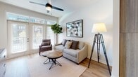Located at 2048 Bolton Dr NW in Atlanta's 30318 zip code, this single-floor residence offers a thoughtfully designed open-concept layout that seamlessly connects the kitchen, dining, and living areas. The kitchen is a standout feature, showcasing a large central island with a crisp white quartz countertop, dual black pendant lights, and a full suite of stainless steel appliances including a refrigerator, range, microwave, and dishwasher. Cabinetry combines white upper cabinets with warm wood-toned lower cabinets, adding modern contrast. Light hardwood flooring flows throughout the living spaces, enhancing the bright, airy feel. The open living area benefits from large windows and a glass-panel door that invite abundant natural light, complemented by a ceiling fan overhead. The bedroom is a calm retreat with neutral tones, a ceiling fan, and a window with shutter blinds. The bathroom features wood-toned cabinetry, a framed mirror, quartz vanity, and a glass-enclosed shower/tub combination with wood-look tile flooring. The overall design aesthetic is clean and contemporary, with a warm, inviting ambiance throughout.