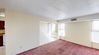 Located at 201 N Pine St in Florence, Alabama, this two-bedroom, one-bathroom unit offers a practical and well-organized single-floor layout. The interior features warm cream-toned walls throughout, paired with plush burgundy-red carpeting that runs consistently across all living areas and bedrooms, lending a cohesive feel to the space. Textured popcorn ceilings are present throughout, along with centralized HVAC vents providing climate control to each room.

The primary bedroom is a comfortable size, featuring a built-in double-door closet for ample clothing storage, along with a second open shelving unit visible through the doorway — ideal for additional organization. Multiple electrical outlets are positioned throughout the room for convenience. The second bedroom benefits from natural light provided by two windows along the exterior wall, brightening the space considerably.

A connecting hallway links the bedrooms to the rest of the unit, maintaining a logical and efficient flow. The bathroom is equipped with a full-size combination tub and shower unit, featuring a sculpted white surround with integrated shelving and chrome fixtures.

The kitchen, visible in the dollhouse overview, is positioned at one end of the unit and appears to include standard cabinetry and countertop workspace. Overall, the unit offers a straightforward, functional living environment with consistent finishes and practical storage solutions throughout.