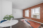 Located at 701 S Gramercy Drive in the heart of Los Angeles, this efficiently designed single-floor unit makes excellent use of its cozy footprint. The main living area is a standout, showcasing a striking exposed red brick accent wall paired with white-framed windows that invite natural light. Wood-look flooring runs throughout, adding warmth and visual continuity across the space.

The kitchen is neatly tucked into a dedicated alcove and is equipped with stainless steel appliances, including a full-size refrigerator and a gas range. White cabinetry, a countertop sink, and an open wall-mounted shelf with a green interior accent complete the functional yet charming setup.

Two bathrooms serve the unit, with at least one featuring classic black-and-white mosaic tile flooring, a full bathtub with shower, a white vanity, and a window for natural ventilation. The clean, all-white palette gives the bathrooms a bright, crisp feel.

The dedicated closet offers thoughtfully organized built-in storage, including a bank of white drawers, a full-length mirror, and a small floating vanity surface — maximizing utility in a compact area.

Throughout the unit, textured white walls and consistent flooring create a cohesive, light-filled ambiance suited for urban living in Los Angeles.