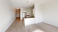 Located in the heart of Hartford, CT, this well-appointed one-bedroom, one-bathroom unit offers a thoughtfully designed single-floor layout with a clean, modern aesthetic throughout. Light wood-style flooring flows seamlessly across the living areas, complementing the bright white walls and creating a cohesive, airy atmosphere.

The open-concept kitchen serves as a central hub, featuring a sleek peninsula with dark countertops, white cabinetry, stainless steel appliances including a refrigerator, and pendant lighting that adds a contemporary touch. The adjacent living area is generously proportioned, bathed in natural light and offering ample space for comfortable furnishing.

The spacious primary bedroom is a standout feature, highlighted by a large black-framed window that frames a striking view of the Connecticut State Capitol and surrounding green space — a rare and impressive urban outlook. The room's clean lines and neutral tones create a calm, restful environment.

The bathroom is finished with large-format tile flooring in soft grey tones, a full soaking tub with shower, a dark-finished vanity with mirror, and crisp white walls accented by a cool blue-grey upper wall. A hallway connects the rooms efficiently, completing this well-organized and modern urban residence.