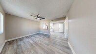 Located at 1750 W Boston St in Chandler, AZ, this well-appointed one-bedroom, one-bathroom residence offers a thoughtfully designed single-floor layout with modern finishes throughout. Light gray wood-look flooring extends across all living areas, complemented by neutral taupe walls, crisp white baseboards, and textured ceilings that lend a clean, contemporary aesthetic.

The open-concept kitchen and living room serves as the heart of the home, with the kitchen showcasing white shaker cabinetry with matte black hardware, gray quartz-style countertops, a subway tile backsplash, stainless steel appliances including a refrigerator, dishwasher, and range, and a single-basin sink beneath a window that invites natural light. A pass-through connects the kitchen to the living area, which features a ceiling fan with light for year-round comfort.

The bedroom is a comfortable, well-proportioned retreat with its own ceiling fan, a window fitted with vertical blinds, and access to generous closet space. Four closets throughout the unit provide abundant storage. A dedicated laundry area houses a stacked washer and dryer, adding everyday convenience. The full bathroom is finished with a white tub-shower combo, a quartz-topped vanity, and matte black fixtures for a modern touch.