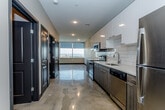 Located at 720 Main St in the heart of downtown Kansas City, Missouri, this modern single-floor unit offers a sleek, contemporary design with thoughtful finishes throughout. The open-concept layout is anchored by polished concrete floors that extend seamlessly across the living and kitchen areas, lending an industrial-chic aesthetic to the space.

The kitchen is a standout feature, equipped with a full suite of stainless steel appliances including a refrigerator, electric range, built-in microwave, and dishwasher. Crisp white upper cabinetry with modern hardware contrasts elegantly with dark wood-grain lower cabinets, while a classic white subway tile backsplash and light quartz countertops complete the refined look. A large window at the end of the kitchen and living area floods the space with natural light and frames views of the Kansas City skyline.

The bathroom is finished with a dark wood-grain vanity, white countertop, a large mirror, and recessed lighting, maintaining the consistent modern palette found throughout the unit. The bedroom features polished concrete flooring, neutral-toned walls, and direct access to the bathroom. An in-unit washer and dryer adds everyday convenience. Recessed lighting throughout ensures a well-lit, polished environment across all areas of this urban residence.