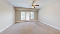 Located at 475 Swanholme Dr in Murfreesboro, TN, this well-appointed one-bedroom, one-bathroom unit offers a practical and comfortable single-floor layout. The combined kitchen and living area forms the heart of the unit, where the kitchen features rich dark wood cabinetry, granite-style countertops, a breakfast bar peninsula with pendant lighting, and black appliances including a range, microwave, refrigerator, and dishwasher. Light hardwood flooring runs through the kitchen, transitioning to neutral wall-to-wall carpet in the living area. The spacious living room is fitted with a ceiling fan and receives natural light through large windows and a glass door that opens to a private balcony. The generously sized bedroom continues the soft carpet flooring, includes a ceiling fan with a window for additional natural light, and provides access to a dedicated walk-in closet outfitted with wire shelving for organized storage. The full bathroom features a single-sink vanity with dark wood cabinetry, a large mirror, tile flooring, and a combined tub and shower. A hallway connects all rooms, completing the efficient and functional floor plan throughout this Murfreesboro residence.